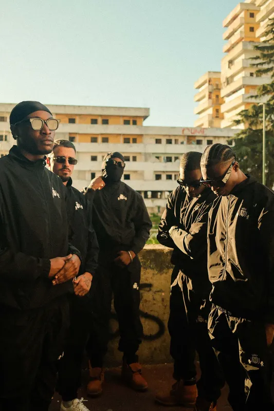 Backstage: il gruppo in tuta nera davanti ai palazzi di Scampia
